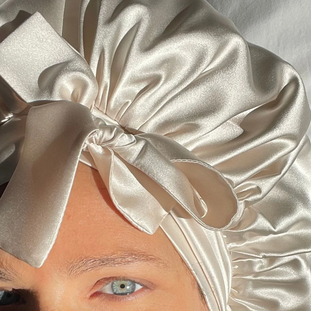 Mujer con gorro de satén color champán para proteger los rizos mientras duerme